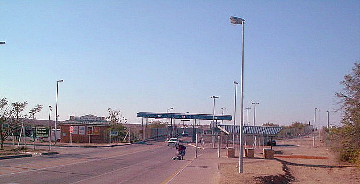 Low buildings, trucks and a bridge.